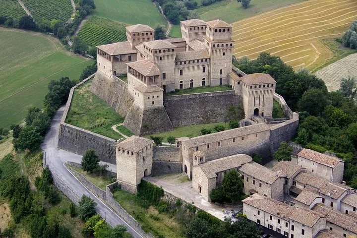 Veduta aerea del Castello di Torrechiara con le sue torri quadrate sopra il borgo e le colline verdi