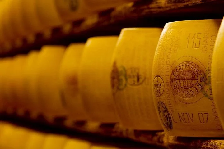Primo piano di forme di Parmigiano Reggiano su scaffali di legno