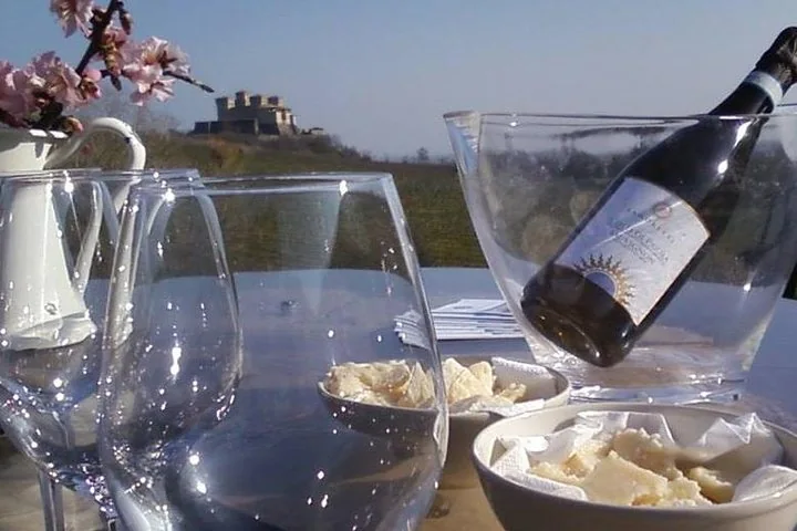 Calici e una bottiglia di vino su un tavolo, con le colline e un castello in lontananza