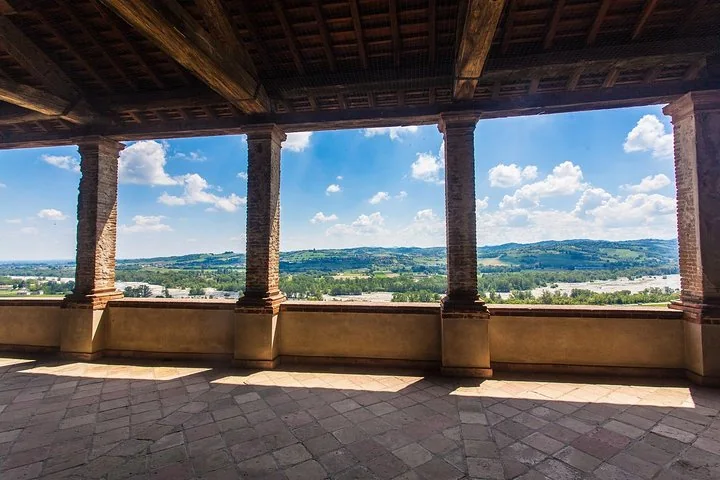 Una loggia con colonne in pietra affacciata sulle colline verdi della val Parma